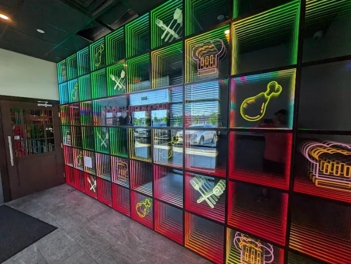 Nori's infinity-mirror neon wall with glowing food icons inside the Westfield restaurant